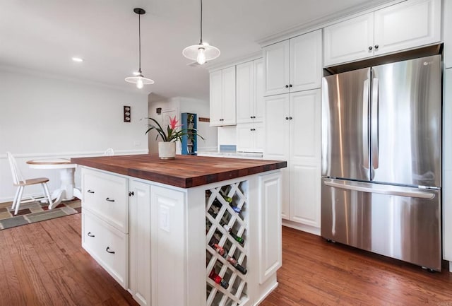 kitchen featuring freestanding refrigerator, white cabinetry, and wood counters