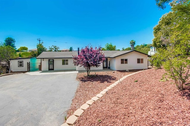 ranch-style house featuring stucco siding, fence, and aphalt driveway