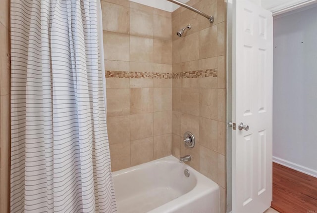 bathroom featuring baseboards, shower / bath combination with curtain, and wood finished floors