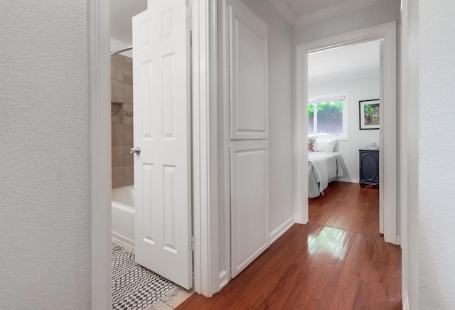 hall with ornamental molding, a textured wall, and wood finished floors