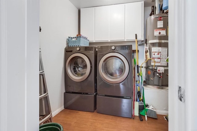 clothes washing area with light wood-style floors, strapped water heater, cabinet space, and washing machine and clothes dryer