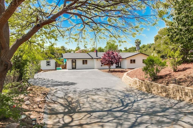 single story home with driveway, an outdoor structure, and stucco siding