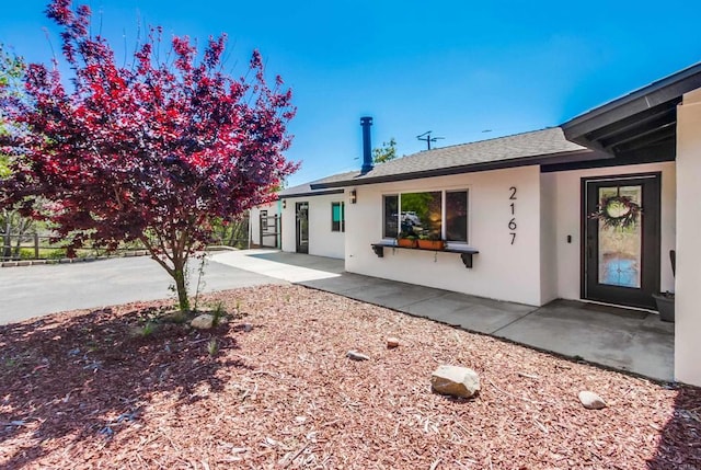 exterior space with roof with shingles, fence, a patio area, and stucco siding