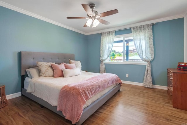 bedroom featuring baseboards, crown molding, and wood finished floors