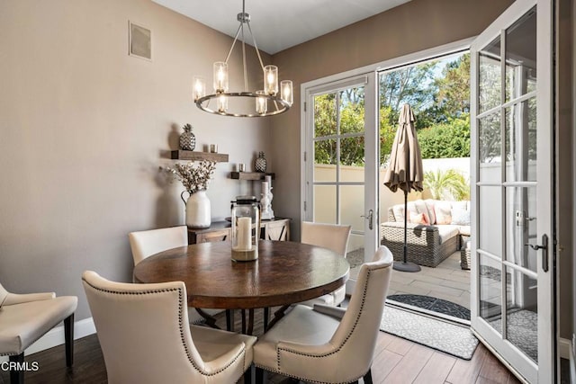 dining room featuring baseboards, visible vents, wood finished floors, and a notable chandelier