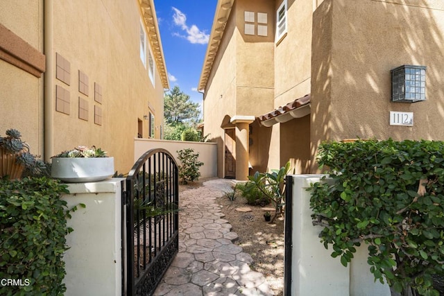 view of side of property with a gate, stucco siding, and fence