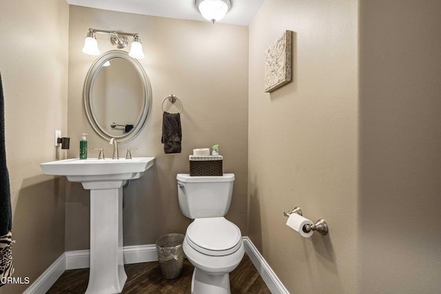 bathroom featuring baseboards, wood finished floors, and toilet