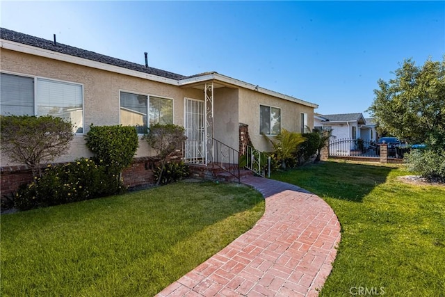 view of front of property featuring fence, a front yard, and stucco siding