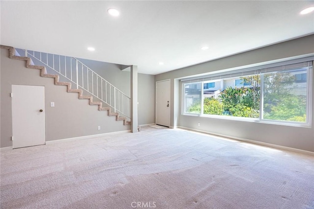 unfurnished living room featuring stairs, baseboards, and carpet
