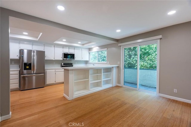 kitchen with white cabinets, appliances with stainless steel finishes, a raised ceiling, light countertops, and baseboards