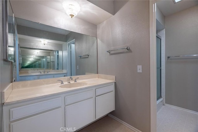 bathroom featuring vanity, baseboards, and a stall shower