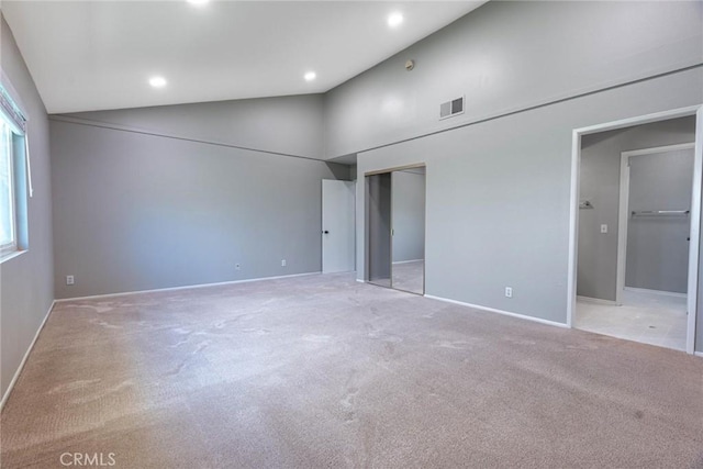 unfurnished bedroom with light colored carpet, high vaulted ceiling, visible vents, and baseboards