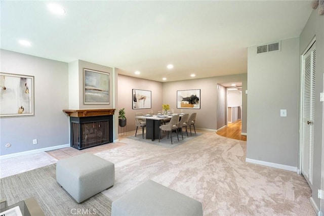 living room with carpet floors, recessed lighting, baseboards, a fireplace with flush hearth, and visible vents