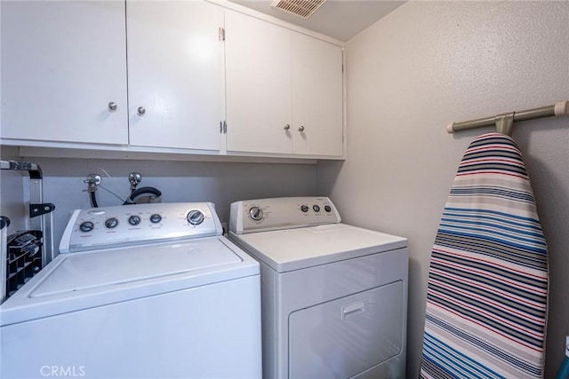 laundry area featuring cabinet space, visible vents, and washing machine and clothes dryer