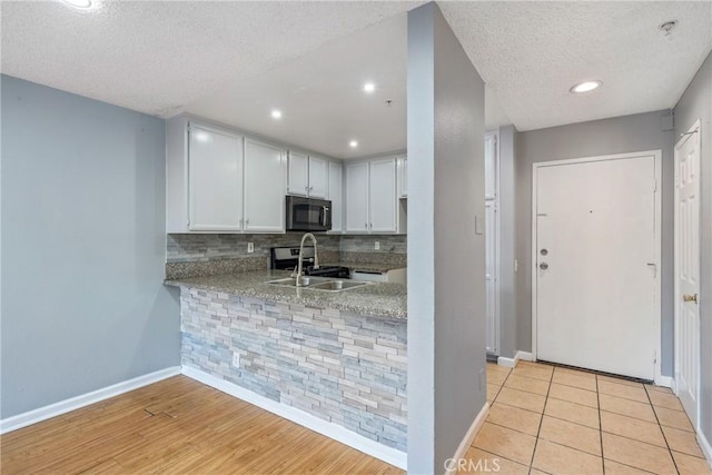 kitchen with baseboards, a textured ceiling, black microwave, and tasteful backsplash