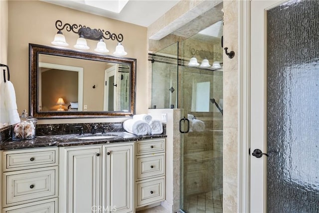bathroom featuring a skylight, vanity, and a shower stall