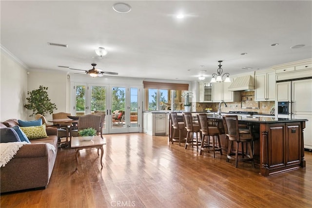 interior space with french doors, visible vents, crown molding, dark wood finished floors, and ceiling fan with notable chandelier