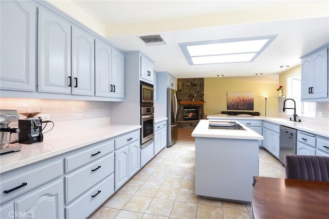 kitchen featuring a sink, stainless steel appliances, decorative backsplash, light countertops, and light tile patterned floors