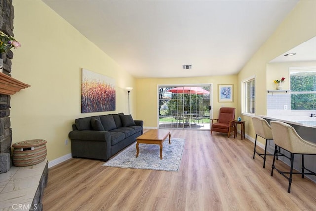living area with wood finished floors, baseboards, vaulted ceiling, and a fireplace