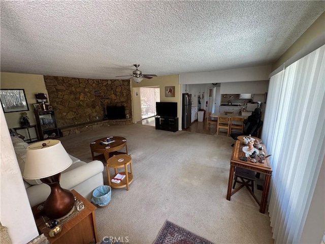 living area featuring a fireplace, ceiling fan, carpet, and a textured ceiling