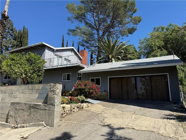 view of front of home featuring aphalt driveway, a balcony, and a garage