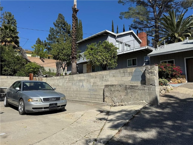 view of side of home with board and batten siding, fence, and a balcony