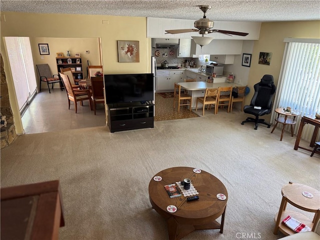 living room with a textured ceiling, ceiling fan, and light carpet