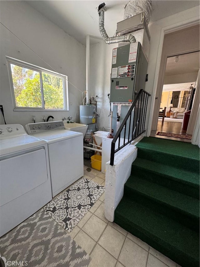 clothes washing area with laundry area, a sink, water heater, light tile patterned flooring, and washer and dryer