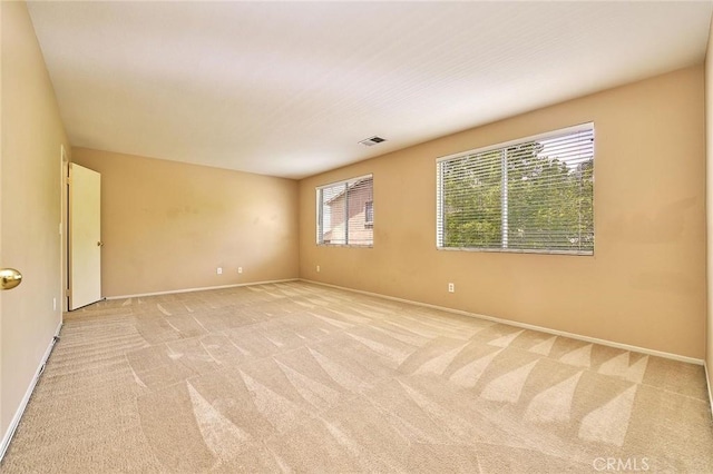 empty room with visible vents, baseboards, and light colored carpet