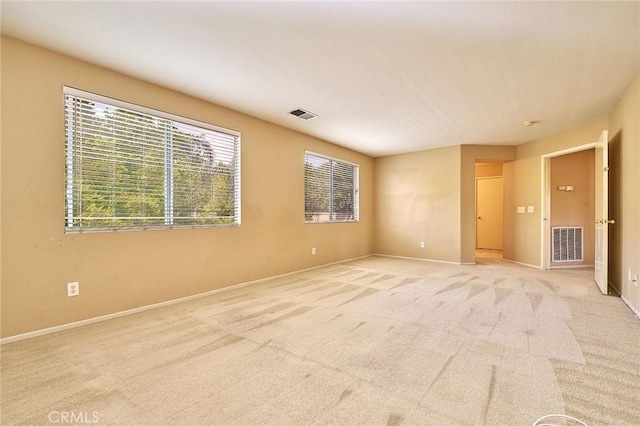 unfurnished room with light colored carpet, baseboards, and visible vents