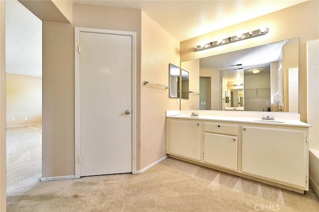 full bath with double vanity, baseboards, a sink, and carpet