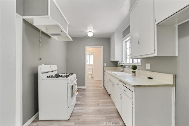 9451 Canterbury Ave, Arleta, CA 91331 - kitchen with white gas range oven, a sink, light countertops, light wood-style flooring, and baseboards