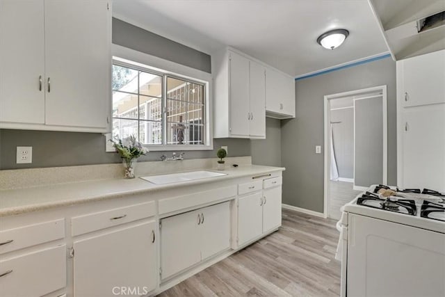 9451 Canterbury Ave, Arleta, CA 91331 - kitchen featuring a sink, white gas range oven, white cabinetry, light wood-style floors, and baseboards