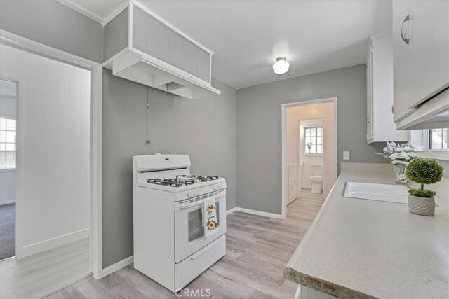 9451 Canterbury Ave, Arleta, CA 91331 - kitchen with gas range gas stove, light countertops, white cabinetry, light wood-style floors, and baseboards