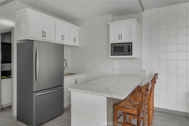 531 Esplanade Unit 714, Redondo Beach, CA 90277 - kitchen featuring appliances with stainless steel finishes, tile walls, light stone counters, white cabinetry, and a sink