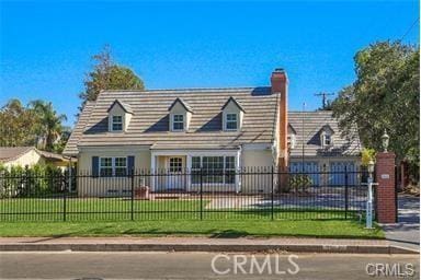 cape cod house featuring a chimney, a fenced front yard, and a front yard