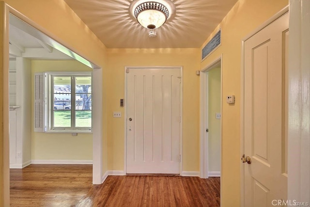 entryway with baseboards, visible vents, and wood finished floors