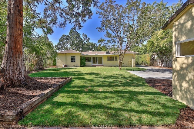 rear view of house featuring a lawn and stucco siding