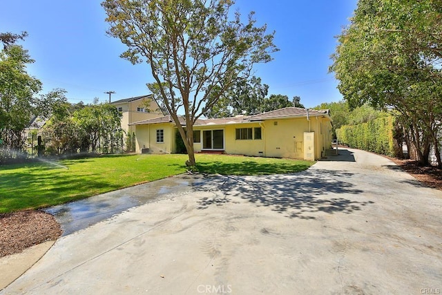 view of front facade featuring a front lawn, stucco siding, and driveway