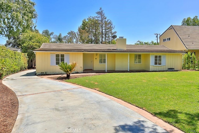 view of front of property with board and batten siding, a chimney, driveway, and a front yard