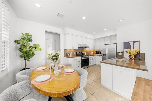 65 Tallowood, Irvine, CA 92620 - kitchen featuring appliances with stainless steel finishes, under cabinet range hood, a sink, a peninsula, and white cabinets