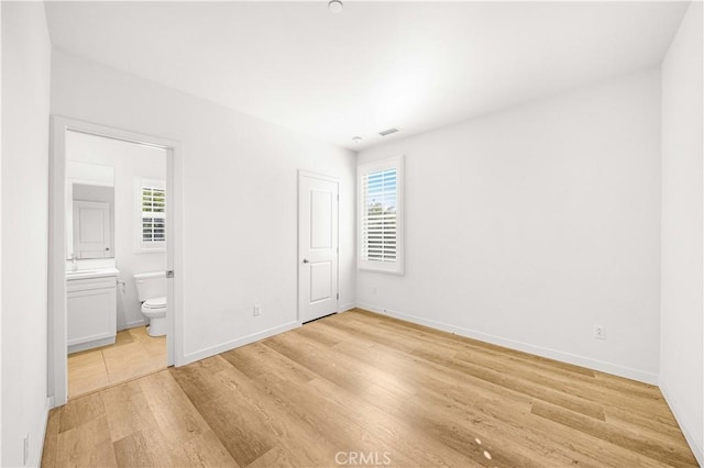 65 Tallowood, Irvine, CA 92620 - unfurnished bedroom featuring multiple windows, light wood finished floors, baseboards, and ensuite bathroom