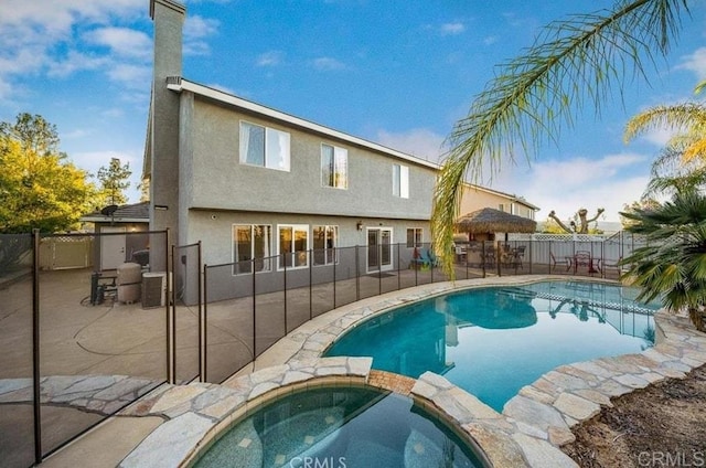 view of pool featuring a patio area, a fenced backyard, a pool with connected hot tub, and central air condition unit