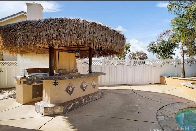view of patio featuring exterior kitchen, fence, and grilling area