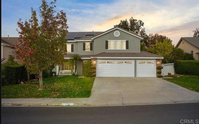 traditional-style house featuring an attached garage, concrete driveway, solar panels, and stucco siding