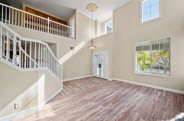foyer with wood finished floors, a high ceiling, stairway, baseboards, and french doors