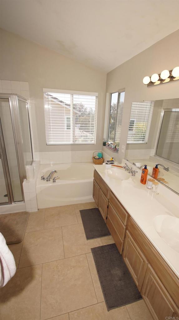 42944 Calle Reva, Temecula, CA 92592 - full bathroom with a garden tub, a shower stall, double vanity, vaulted ceiling, and tile patterned flooring