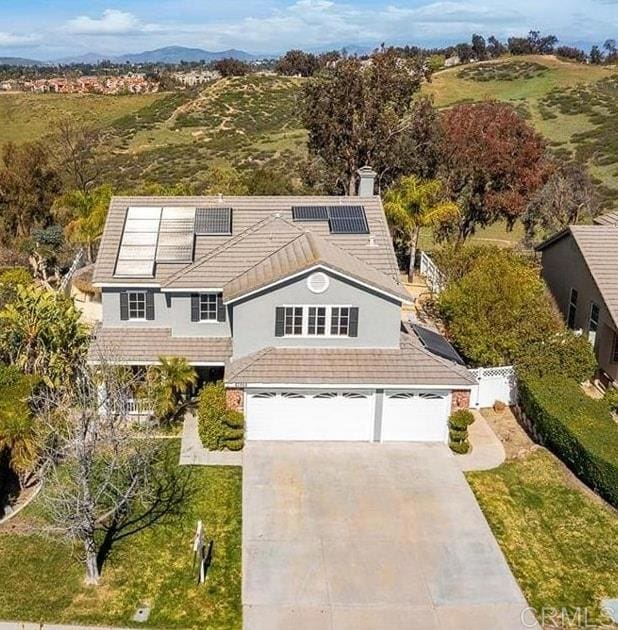 42944 Calle Reva, Temecula, CA 92592 - view of front facade with concrete driveway, a garage, roof mounted solar panels, and a chimney