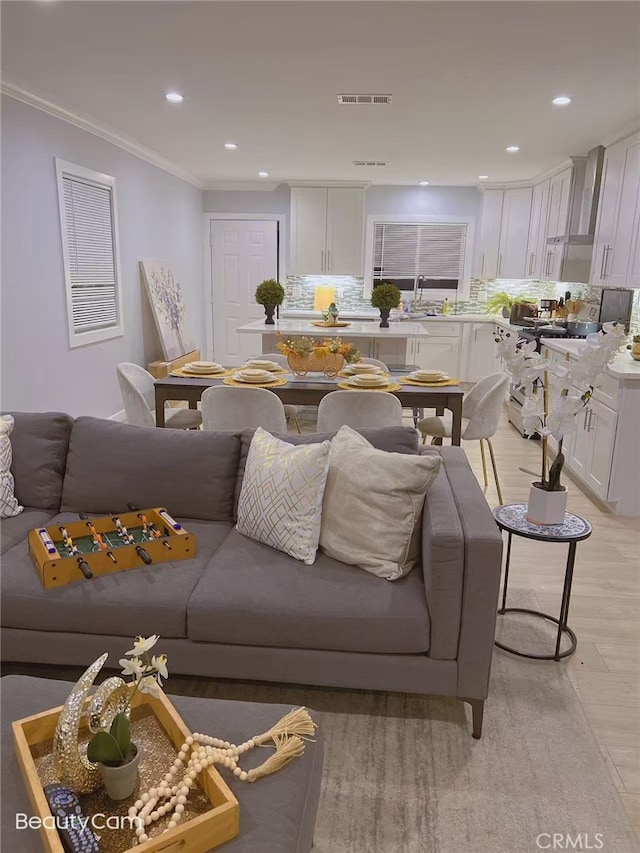 living area featuring visible vents, recessed lighting, crown molding, and light wood-type flooring
