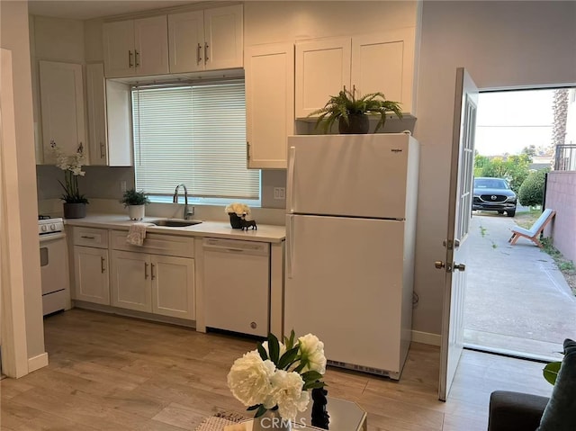 kitchen with light wood-style floors, a sink, white appliances, and light countertops
